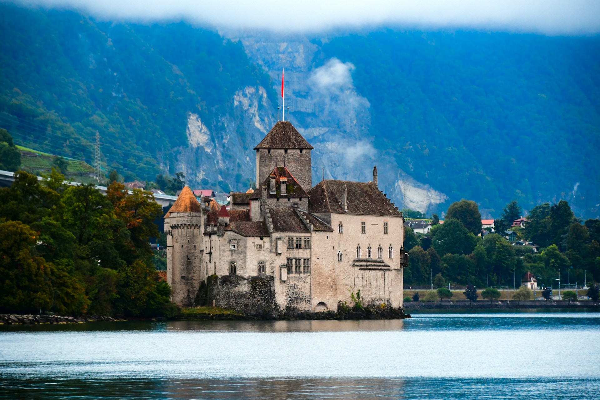 Montreux lakeside promenade with palm trees and the Château de Chillon on Lake Geneva